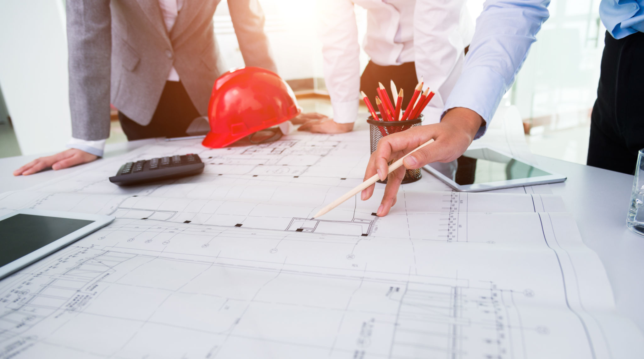 Grupo de arquitetos e engenheiros discutindo planos de construção em torno de uma mesa